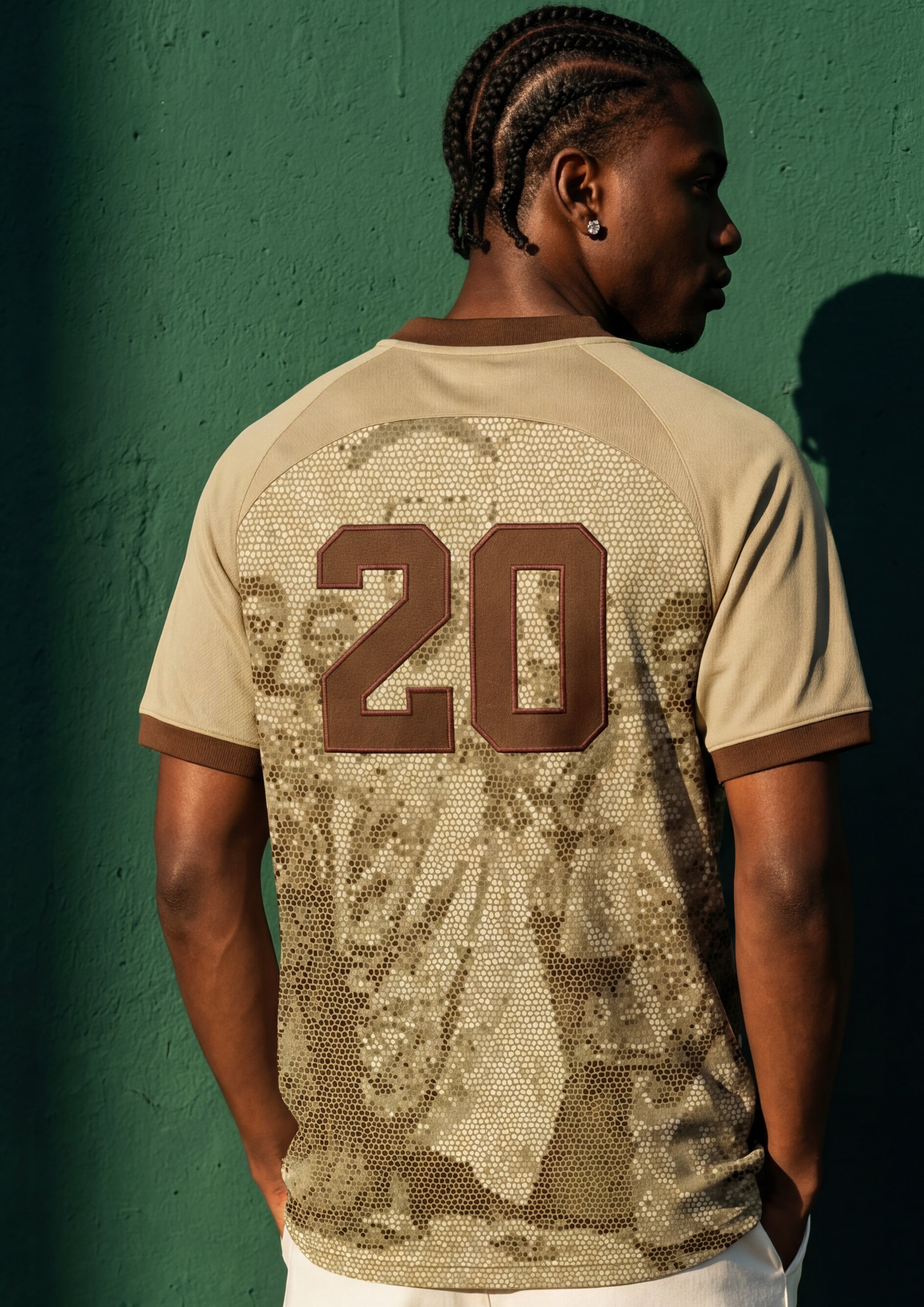 Black men wearing a beige soccer jersey with number twenty on the back